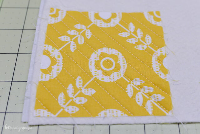yellow square fabric sewn to the corner of batting right side up