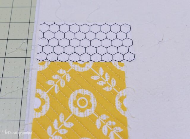 quilted fabric strip on each side of a fabric square on backing fabric