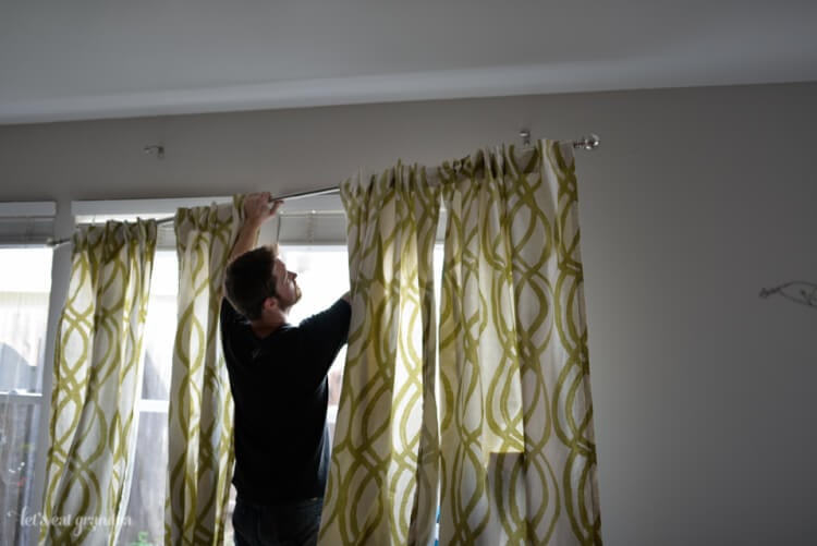 man holding curtain rod to hang curtains