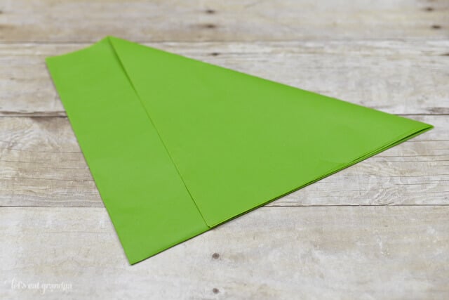 green tissue paper sheet on wooden background with corner folded over