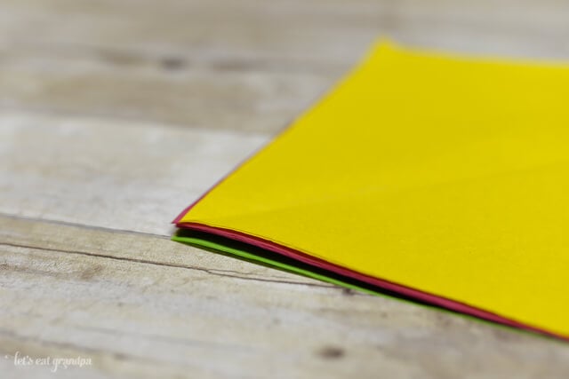 magenta, yellow, and green tissue paper sheet stacked on wooden background