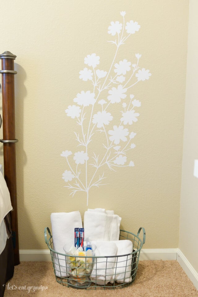 floral decal on wall with small basket of guest room necessities 