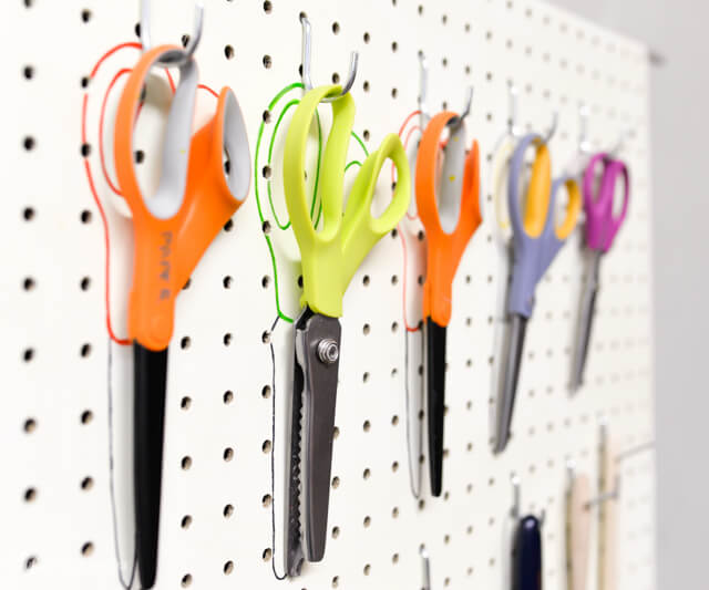 scissors hanging from pegboard with colorful sharpie outline behind them