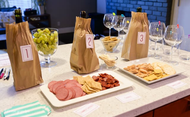 wine in brown bags with numbered labels and snack trays on counter