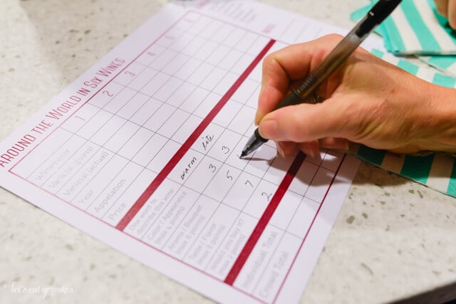 person's hand filling out wine tasting sheet at wine party