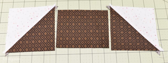 brown and white fabric pieces laid on sewing mat to make acorn block quilt pillow