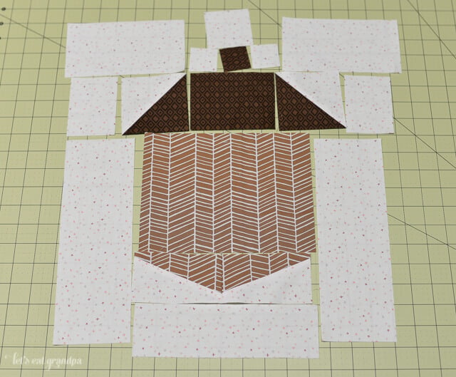 brown and white fabric pieces cut and laid on sewing mat to make acorn block quilt pillow