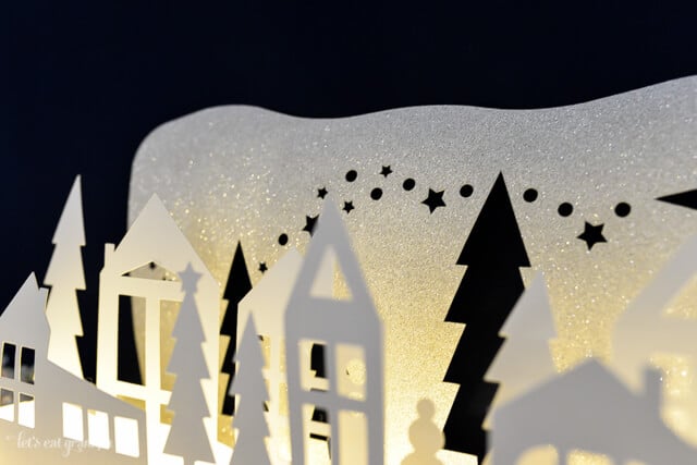 A close up of a Christmas themed luminaria cut from paper