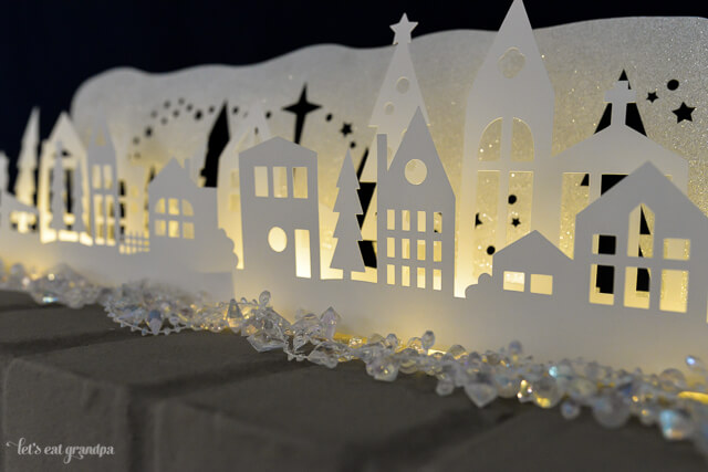 A close up of a Christmas themed luminaria cut from paper