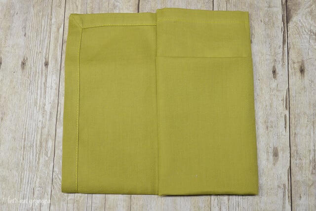 green napkin folded in half and one sided folded in