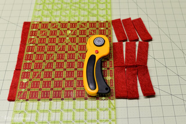rotary cutter, cutting mat and strips of red felt cut 