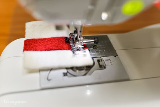sewing machine sewing red and white felt strips together