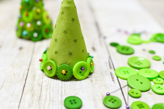 row of buttons placed on fabric cone to make Christmas button foam craft